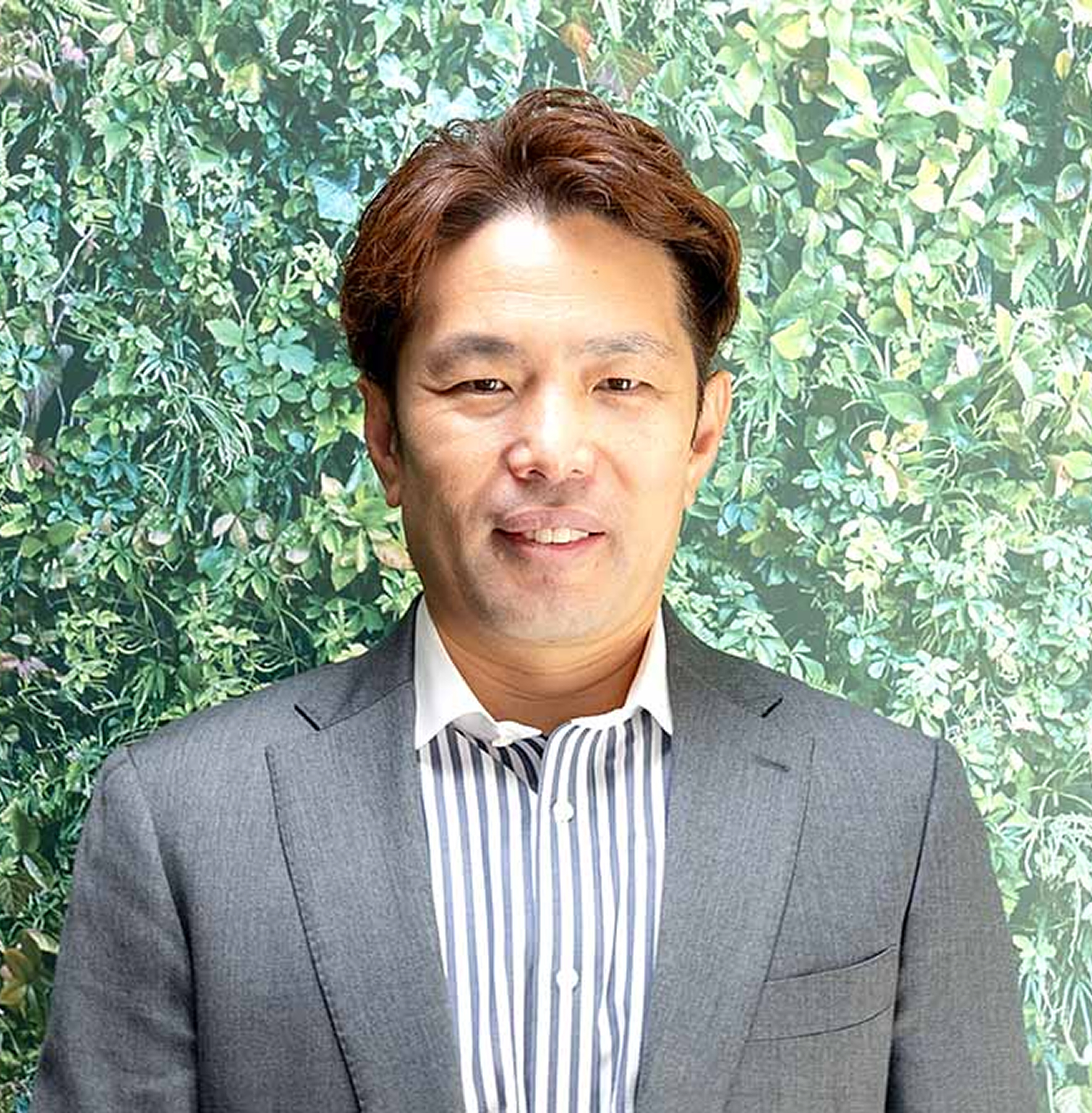 スーツを着た男性が笑顔で立っている様子