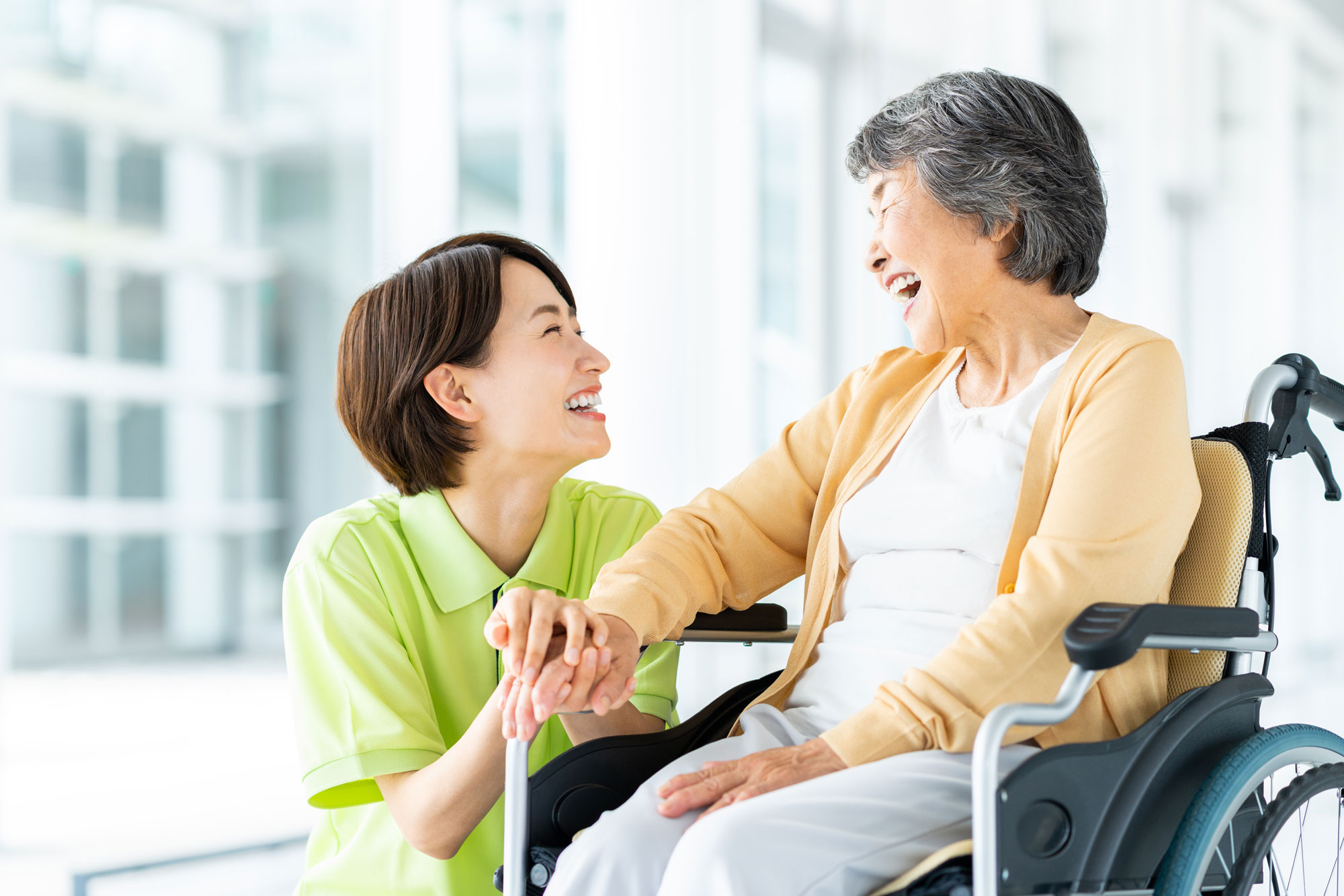 車椅子の高齢者と笑顔で話す介護士